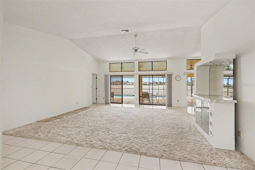 A spacious living room features white carpeting, a built-in wet bar, and sliding glass doors — 423 SW 12TH STREET, CAPE CORAL, FL