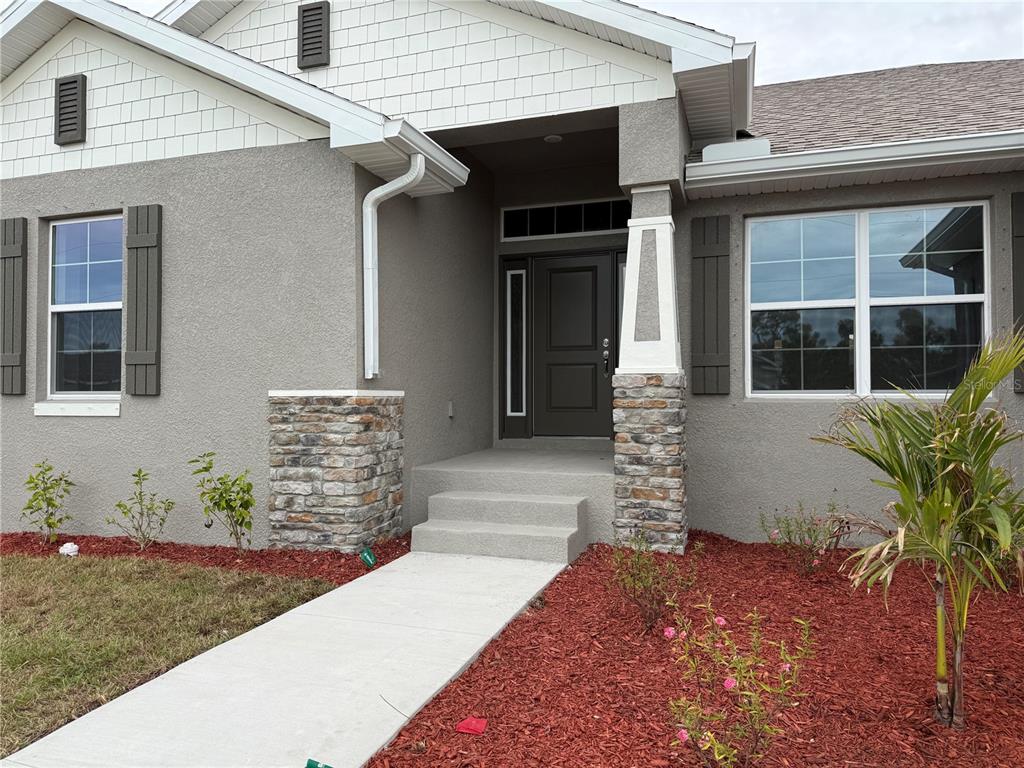 The exterior of a house features a gray stucco facade, stone-accented columns, and a front entryway — 14184 SALVATIERRA LANE, PORT CHARLOTTE, FL