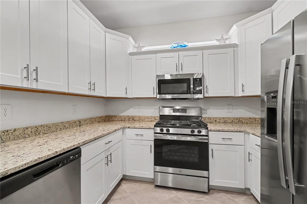 A kitchen with white cabinets, stainless steel appliances, and speckled granite countertops — 17848 PALMETTO PASS LANE, PUNTA GORDA, FL