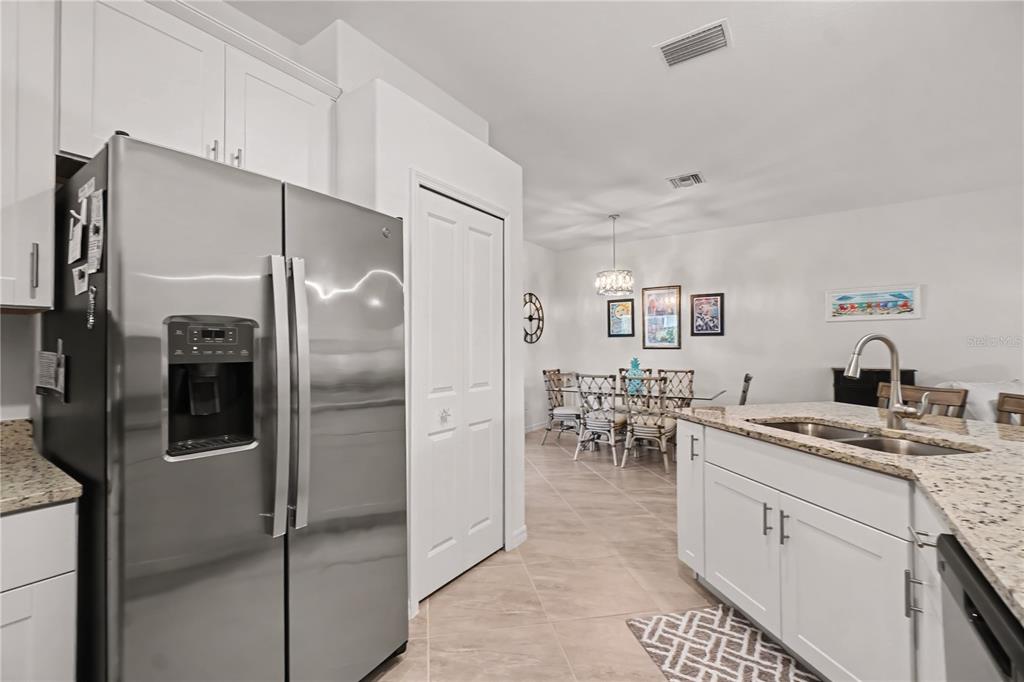 A kitchen with white cabinets, stainless steel appliances, and granite countertops overlooks a dining area — 17848 PALMETTO PASS LANE, PUNTA GORDA, FL