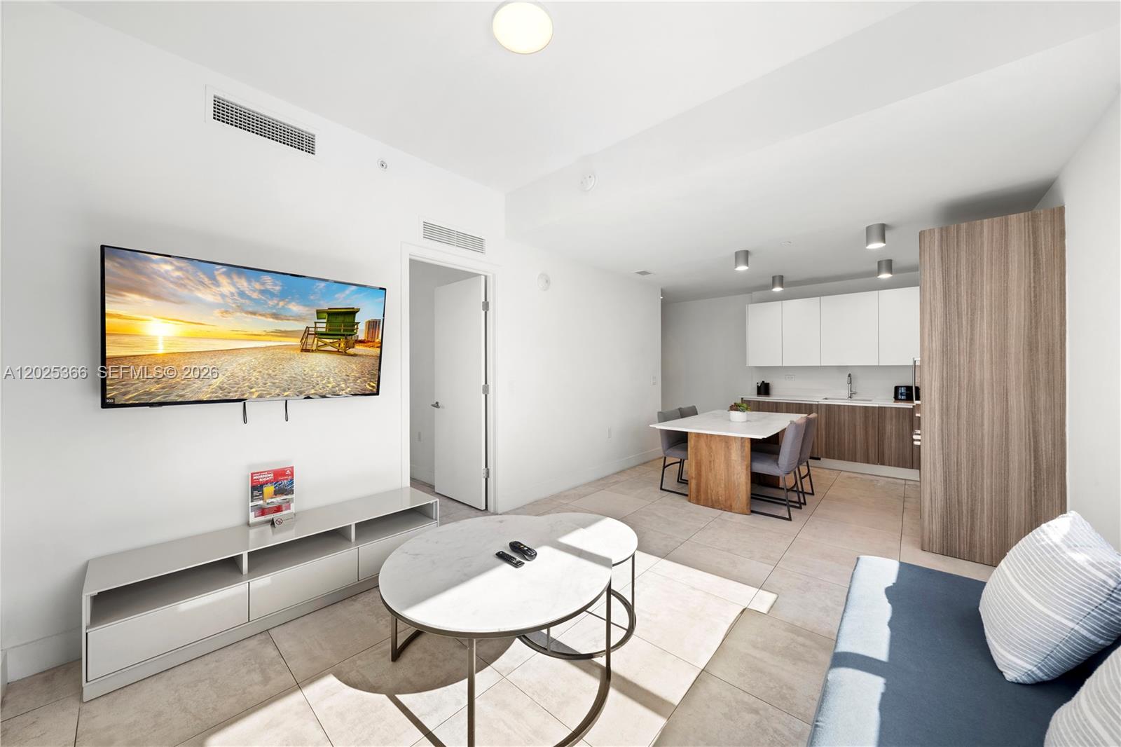 A modern open-concept living area features a television, dining table, and kitchen with light flooring — 239 SW 9th St # 1701, Miami FL 33130, MIAMI, FL