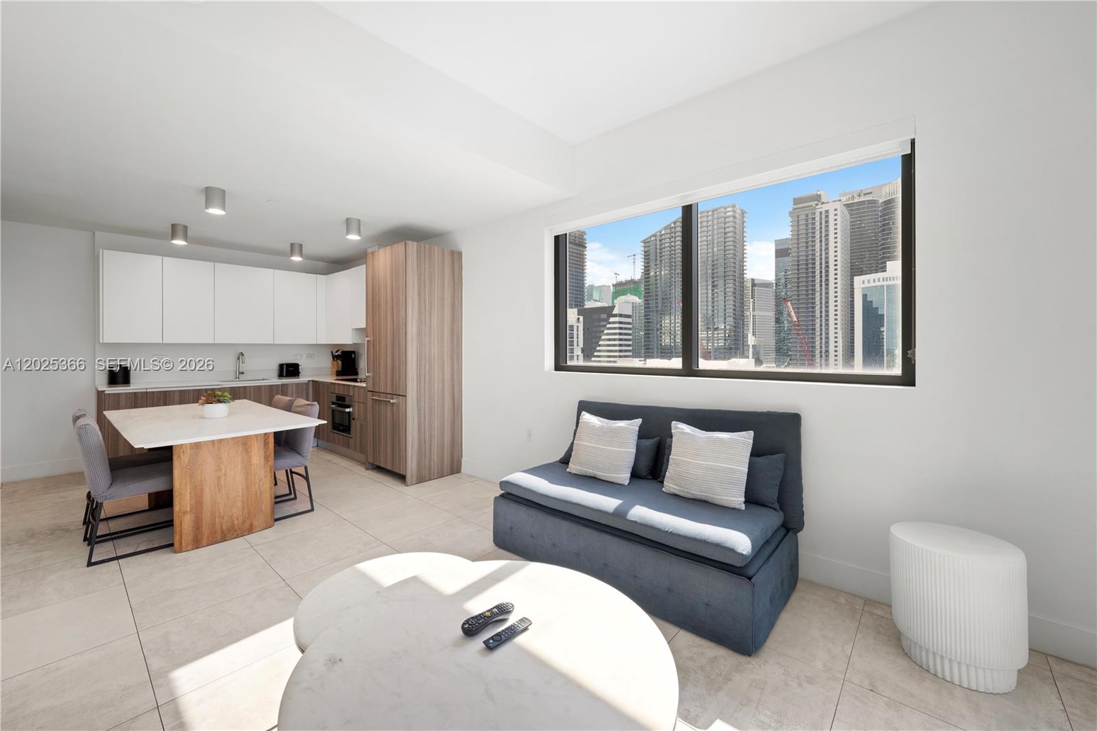 A modern studio apartment features a kitchen with wood cabinetry and a city view window — 239 SW 9th St # 1701, Miami FL 33130, MIAMI, FL
