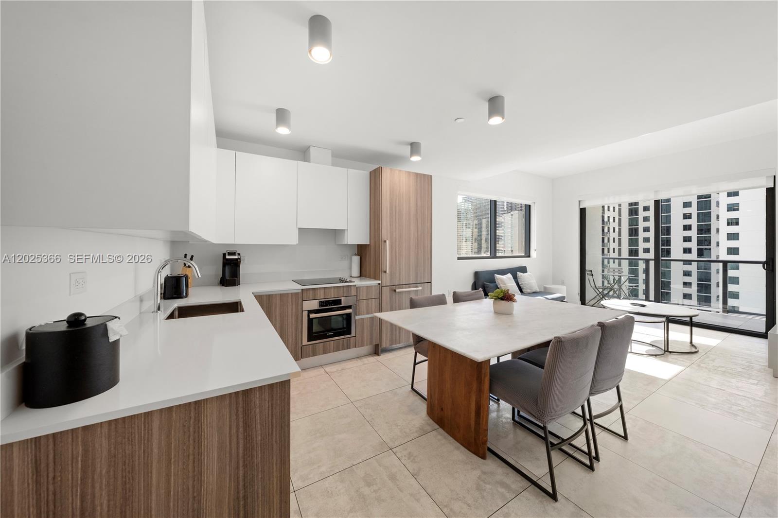 A modern kitchen and dining area feature white countertops, wood cabinetry, and a balcony view — 239 SW 9th St # 1701, Miami FL 33130, MIAMI, FL
