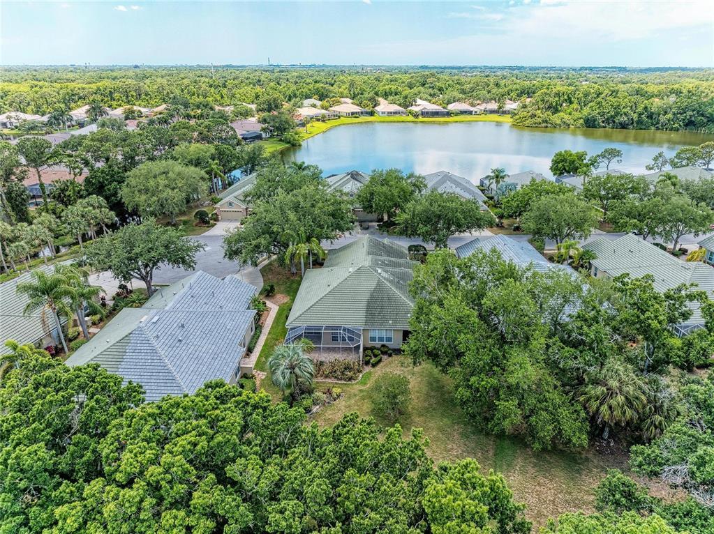 An aerial view shows several suburban houses with green roofs situated near a lake — 5047 LAKESCENE PLACE, SARASOTA, FL