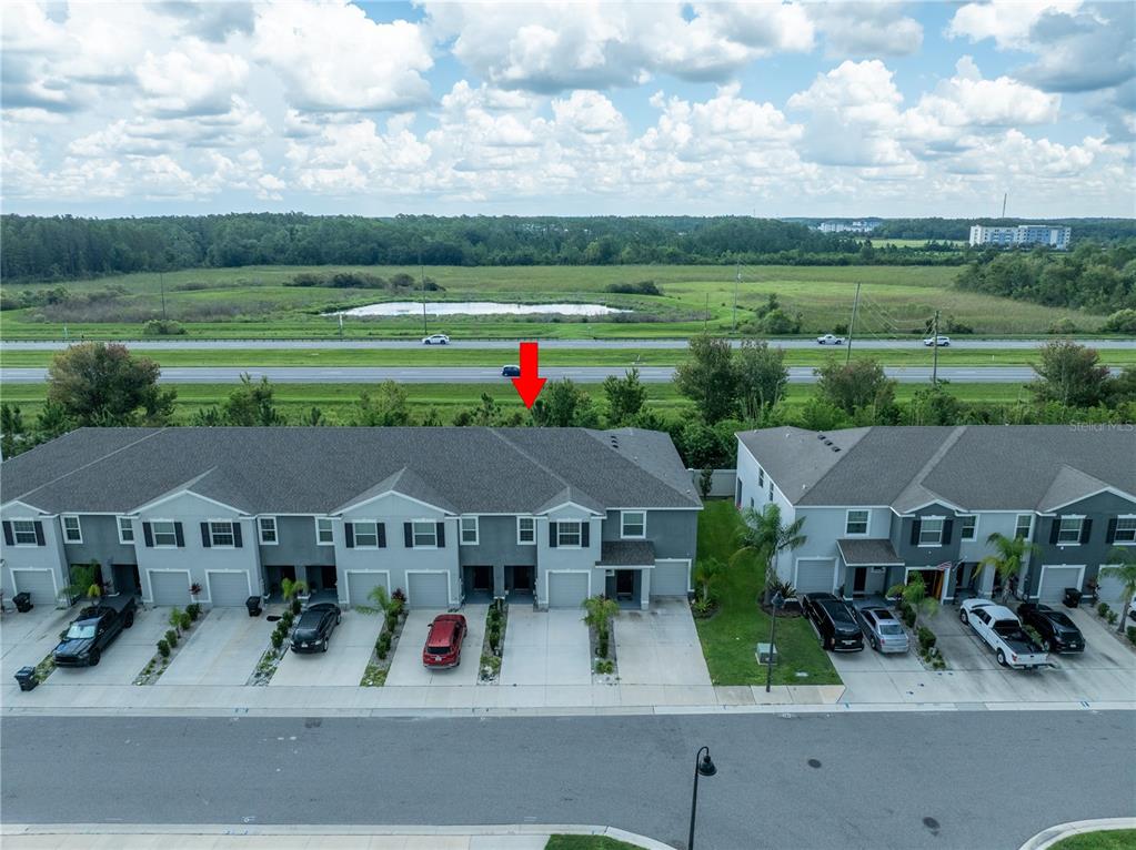 An aerial view shows a row of townhouses with a red arrow pointing toward the roof — 2886 SUNCOAST PLAINS DRIVE, ODESSA, FL