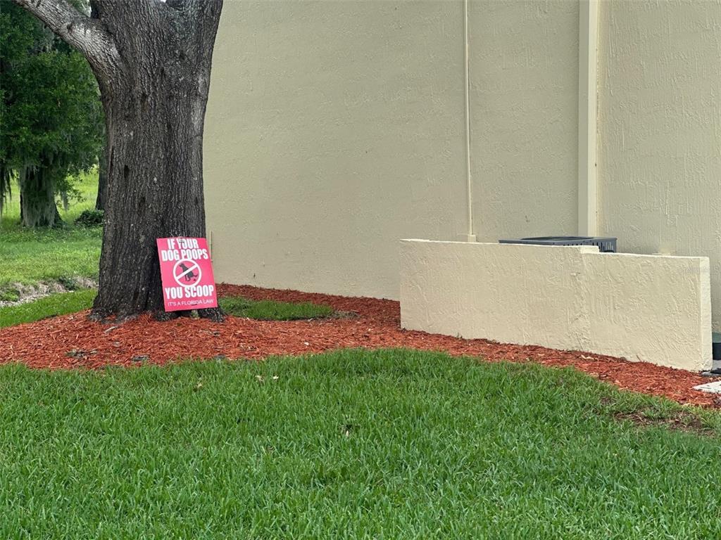A pink sign about cleaning up after dogs sits on red mulch near a tree — 6118 TOPHER TRAIL UNIT 6118, MULBERRY, FL