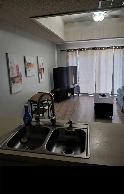 A kitchen sink overlooks a living room with a television, dining table, and sliding doors — 6118 TOPHER TRAIL UNIT 6118, MULBERRY, FL