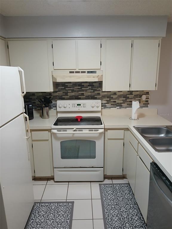 A kitchen with white cabinets, a white electric stove, and a tiled backsplash — 6118 TOPHER TRAIL UNIT 6118, MULBERRY, FL