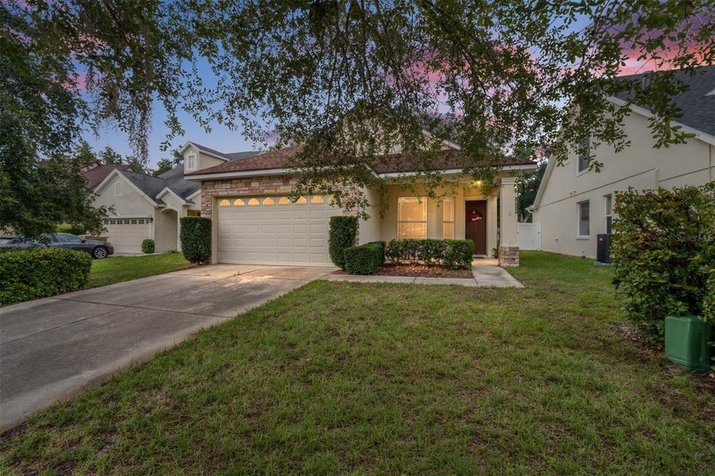 A single-story house with a stone facade, a two-car garage, and a front lawn — 10217 GRANITE COURT, LEESBURG, FL