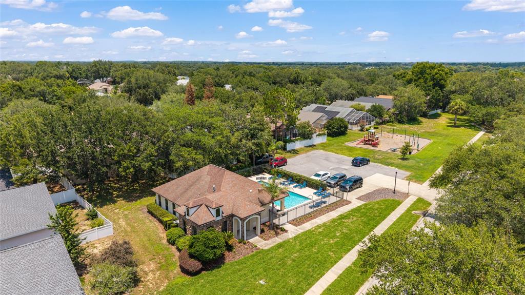 An aerial view shows a community clubhouse with a swimming pool, parking lot, and playground — 10217 GRANITE COURT, LEESBURG, FL