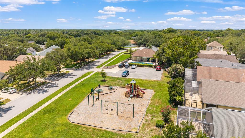 An aerial view shows a neighborhood playground, a community pool building, and surrounding houses — 10217 GRANITE COURT, LEESBURG, FL