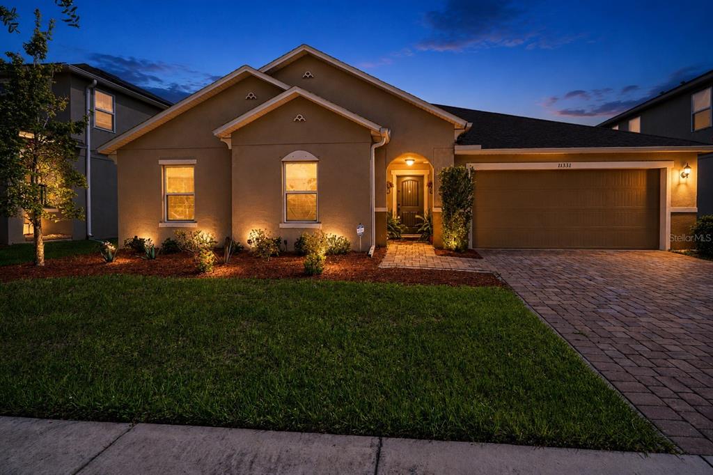 A single-story house exterior at dusk features a paved driveway, garage, and landscaped front yard — 11331 BRIGHTON KNOLL LOOP, RIVERVIEW, FL
