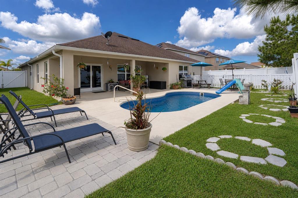 A backyard features a swimming pool, a paved patio with lounge chairs, and a grassy lawn — 11331 BRIGHTON KNOLL LOOP, RIVERVIEW, FL