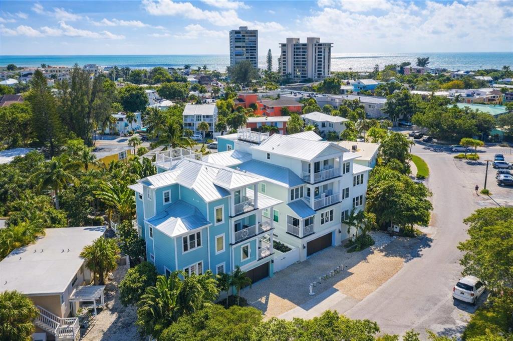 An aerial view shows a multi-story light blue house with a metal roof near the ocean — 332 AVENIDA DE MAYO, SARASOTA, FL