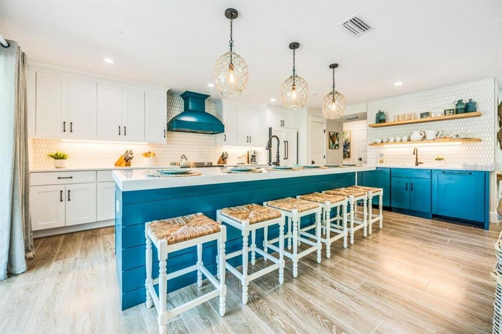 A kitchen with white cabinets, a teal island with bar stools, and open wood shelving — 332 AVENIDA DE MAYO, SARASOTA, FL