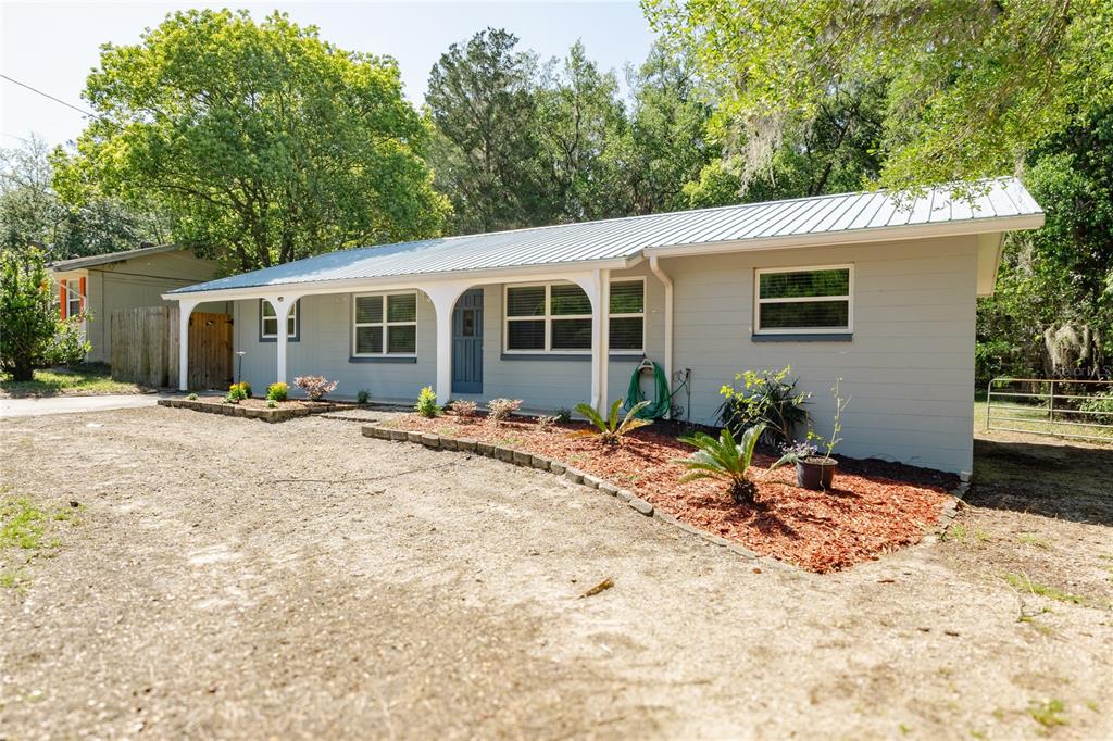 A single-story gray house with a metal roof and a covered front porch — 24270 SW SHOREWOOD DRIVE N, DUNNELLON, FL