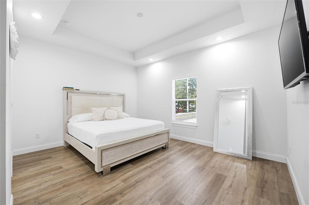 A bedroom features a light-colored bed, wood-look flooring, a large floor mirror, and recessed lighting — 524 S GROSSE AVE AVENUE, TARPON SPRINGS, FL