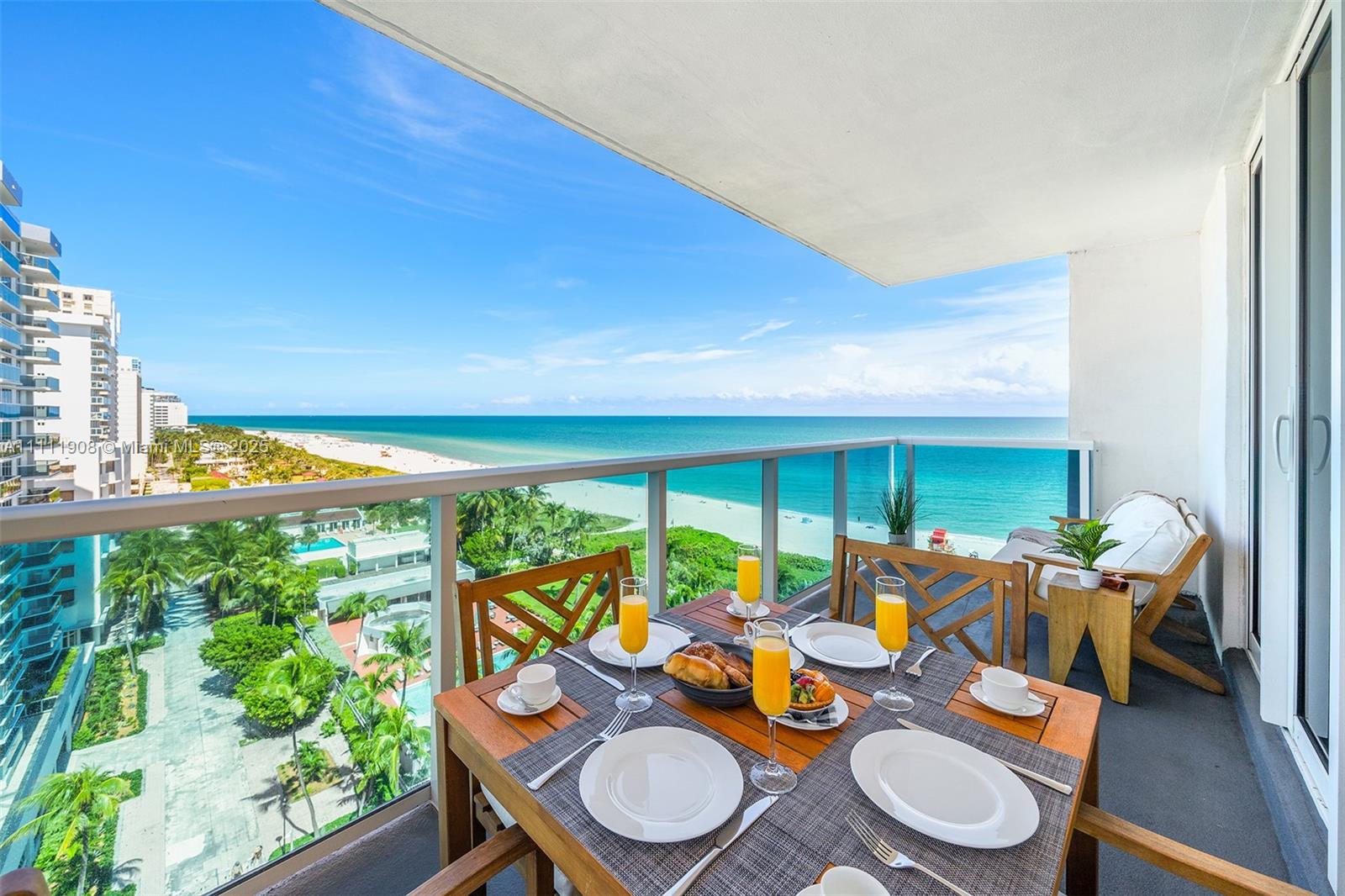 A balcony with a dining set overlooks a beach and the ocean — 102 24th St # 1019, Miami Beach FL 33139, MIAMI BEACH, FL