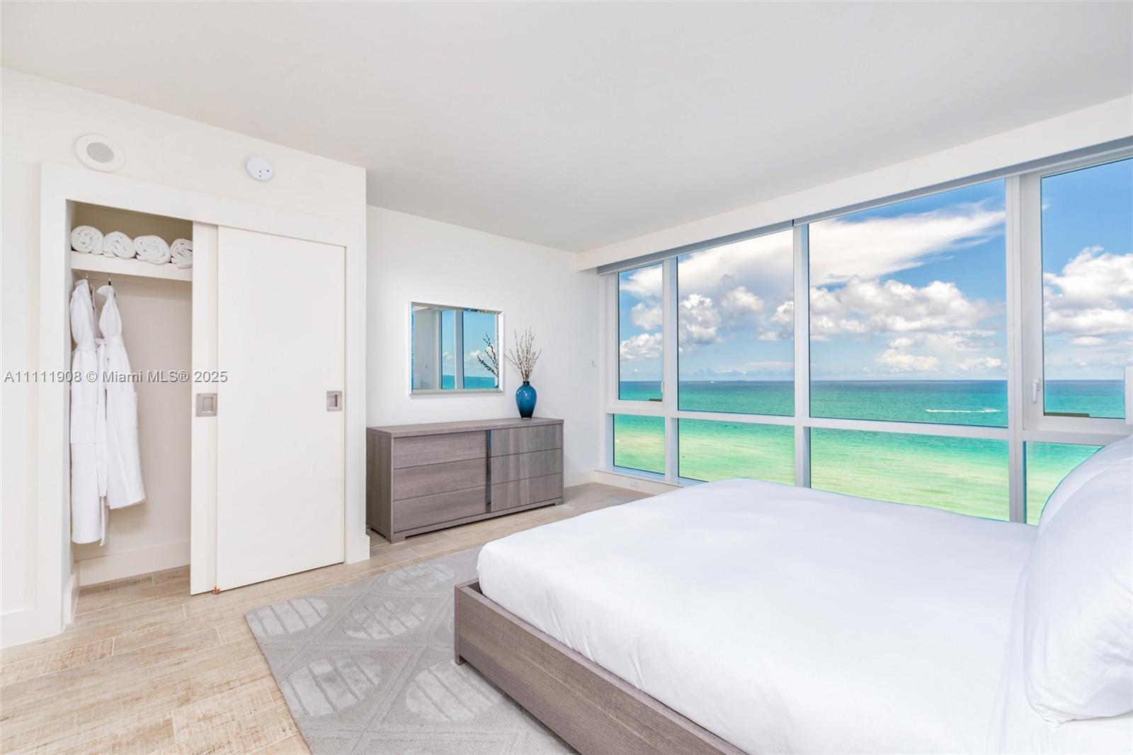 A bedroom features a bed, a dresser, a closet, and floor-to-ceiling windows overlooking the ocean — 102 24th St # 1019, Miami Beach FL 33139, MIAMI BEACH, FL