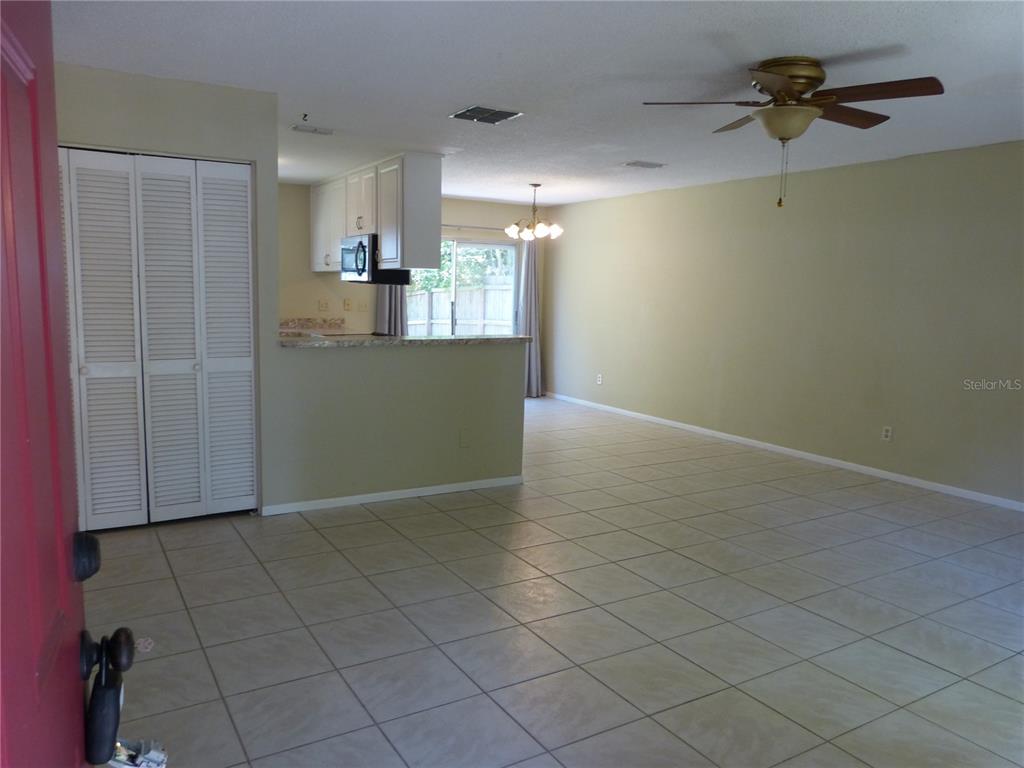 An open-concept living and dining area features tile flooring, a ceiling fan, and a kitchen — 2528 ELDERBERRY DRIVE, CLEARWATER, FL