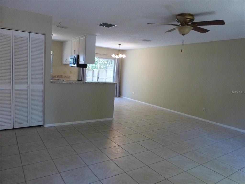 An open-concept living area features light-colored tile flooring, beige walls, and a kitchen pass-through — 2528 ELDERBERRY DRIVE, CLEARWATER, FL