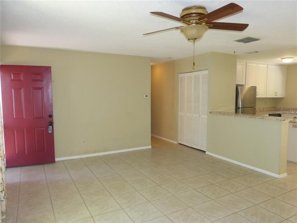 An interior view shows a tiled living area with a red door and kitchen pass-through — 2528 ELDERBERRY DRIVE, CLEARWATER, FL