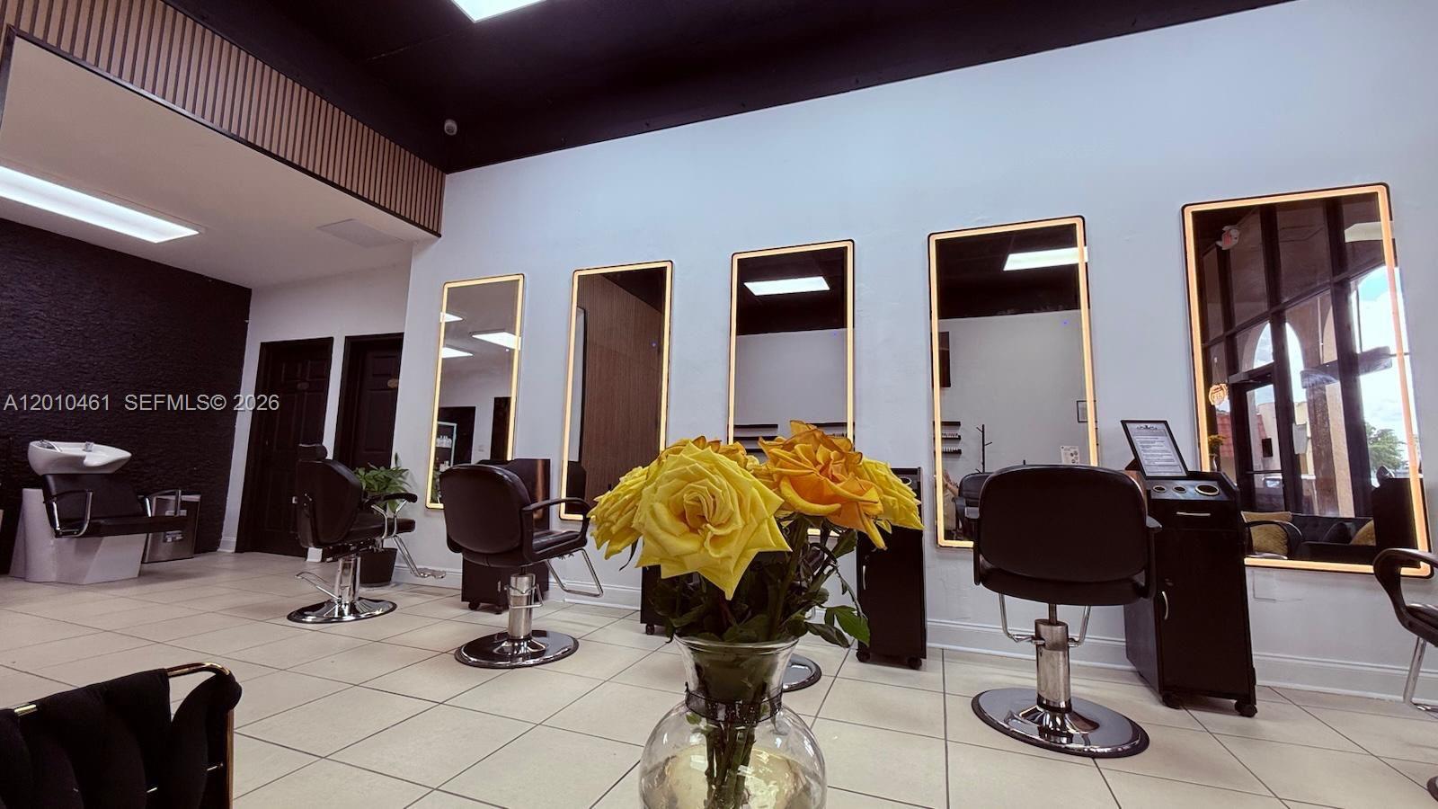 A hair salon interior features multiple styling stations with illuminated mirrors and black leather chairs — 9610 Fontainebleau Blvd, Miami FL 33172, MIAMI, FL