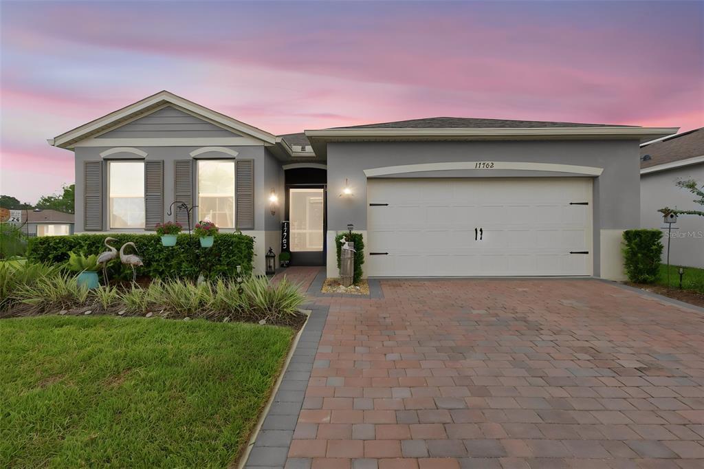 A single-story house with a gray exterior, a two-car garage, and a brick paver driveway — 17762 BLAZING STAR CIRCLE, CLERMONT, FL