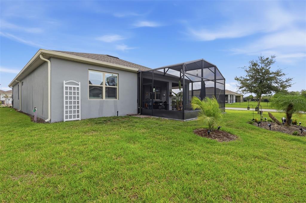 The exterior rear view of a single-story house features a screened-in lanai and grassy yard — 17762 BLAZING STAR CIRCLE, CLERMONT, FL