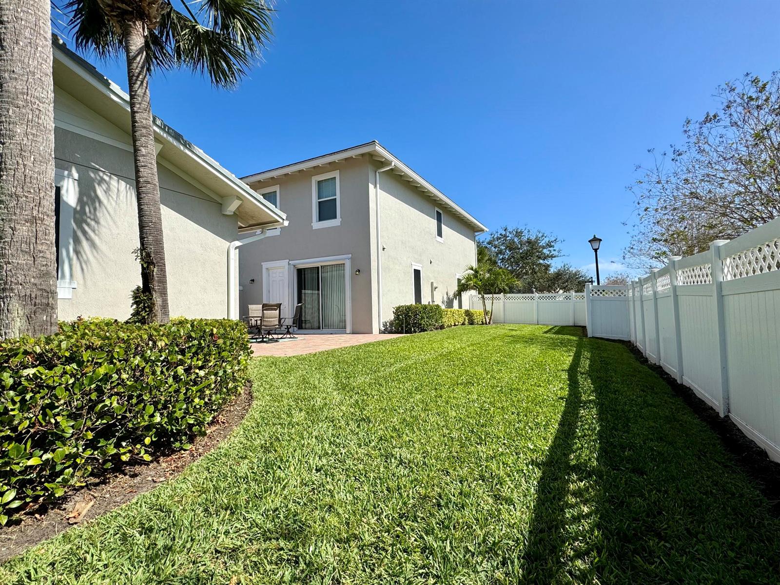 A backyard with a green lawn, a patio, and a white vinyl privacy fence — 2758 Avalon Way, Jupiter FL 33458, JUPITER, FL
