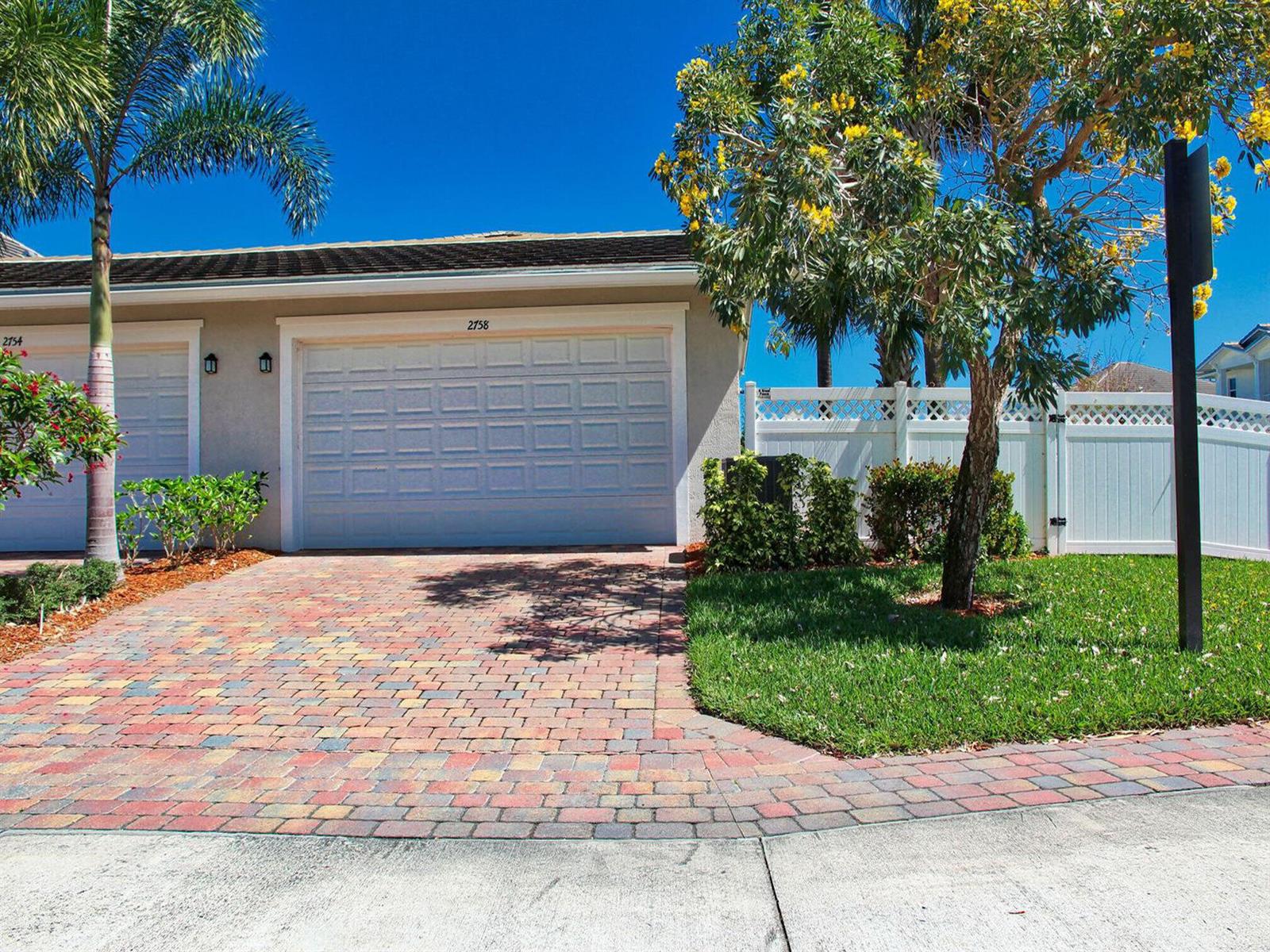 A paved driveway leads to a single-story home with a garage and a white fence — 2758 Avalon Way, Jupiter FL 33458, JUPITER, FL