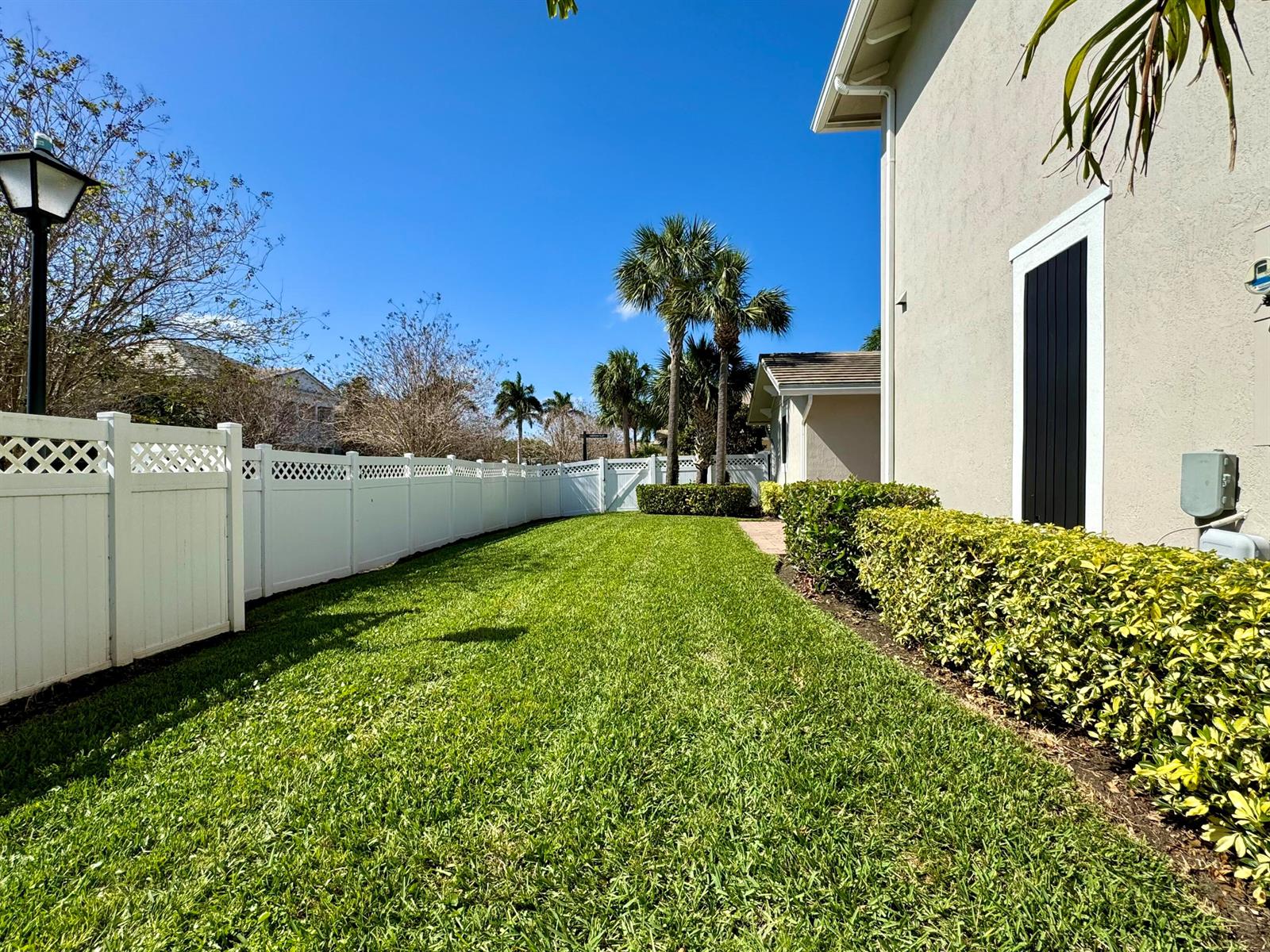 A side yard features a green lawn, a white vinyl fence, and a manicured hedge — 2758 Avalon Way, Jupiter FL 33458, JUPITER, FL