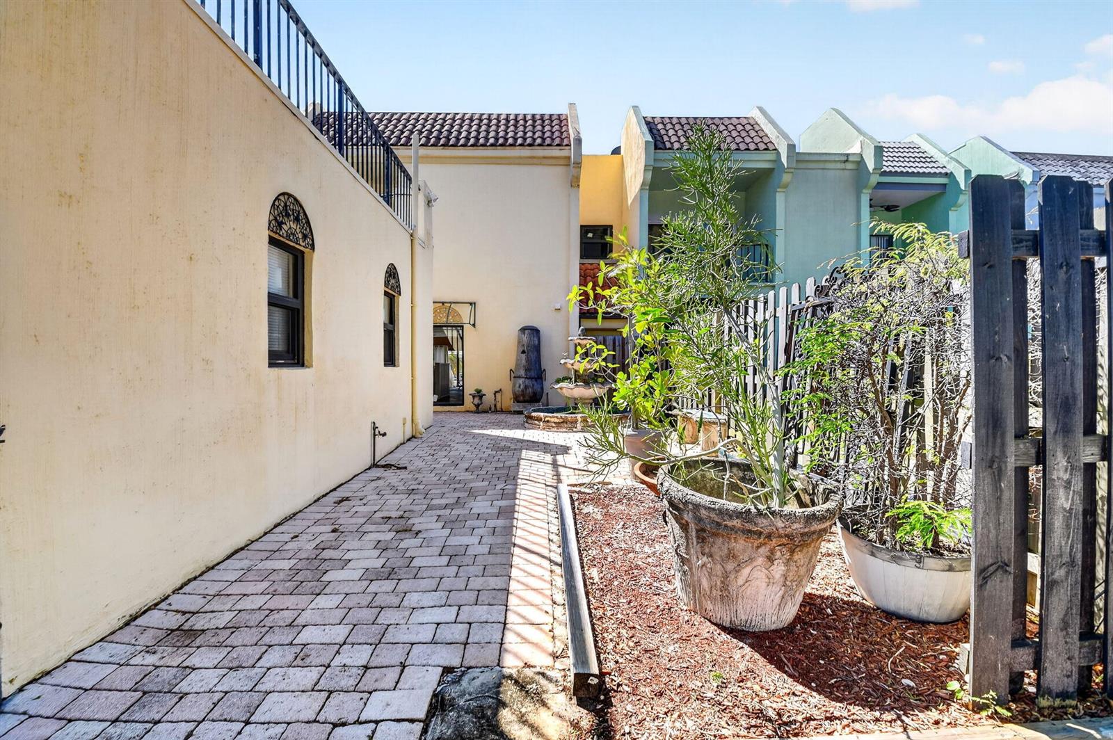 A paved walkway leads to a courtyard with a fountain and potted plants — WELLINGTON, FL