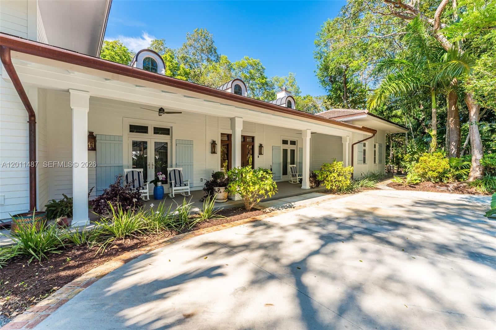 A white house with a covered porch, blue shutters, and a concrete driveway — 4901 Hammock Park Dr, Coral Gables FL 33156, CORAL GABLES, FL