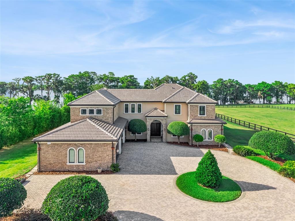 A horse stable aisle with four stalls, wood-paneled ceilings, and a view of a lake — 746 LAKE MILLS ROAD, OVIEDO, FL