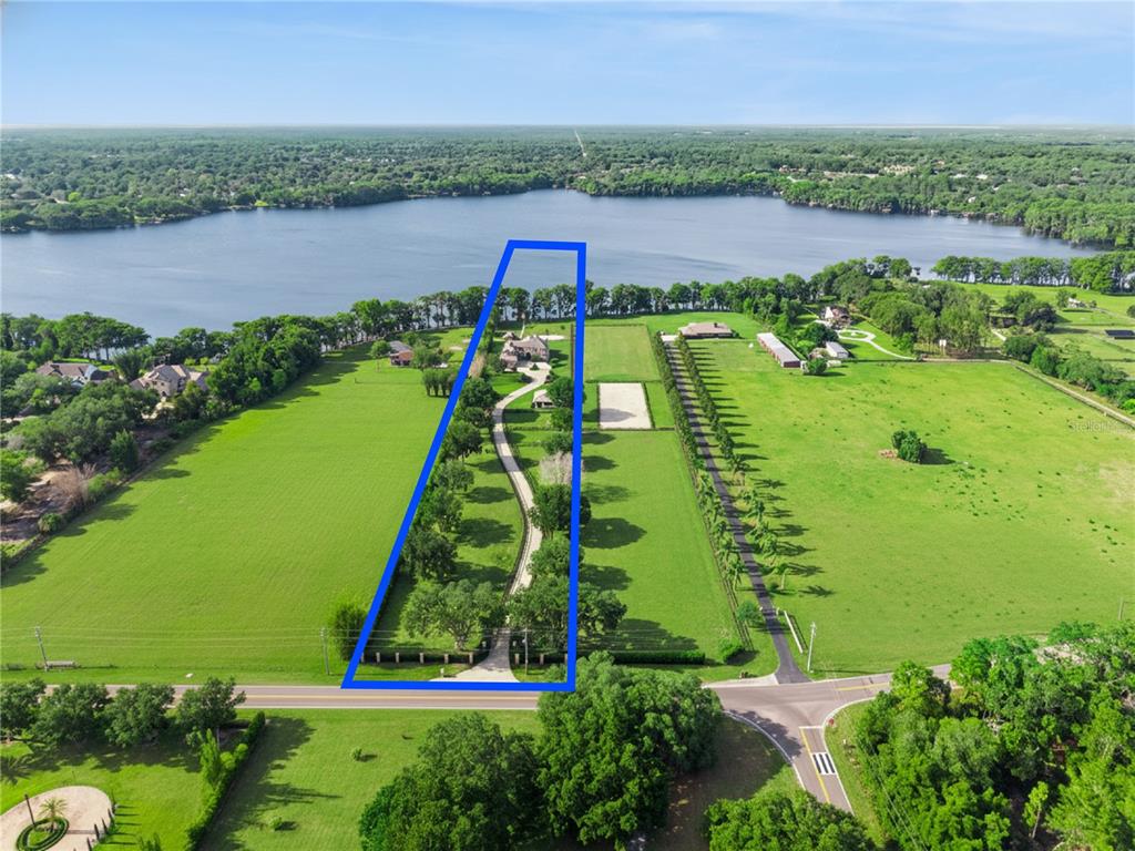 An aerial view of a two-story stone and stucco house with a circular driveway — 746 LAKE MILLS ROAD, OVIEDO, FL