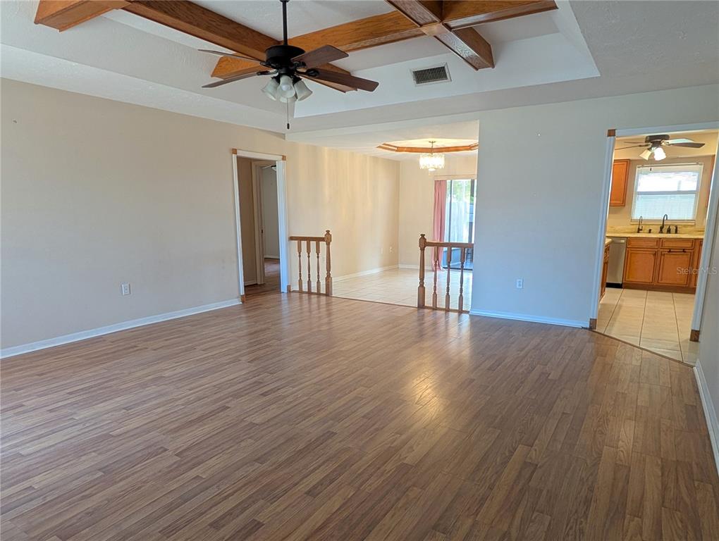A spacious living area features wood-look flooring, a coffered ceiling with beams, and a kitchen — 88 TEMPLE ROAD, VENICE, FL