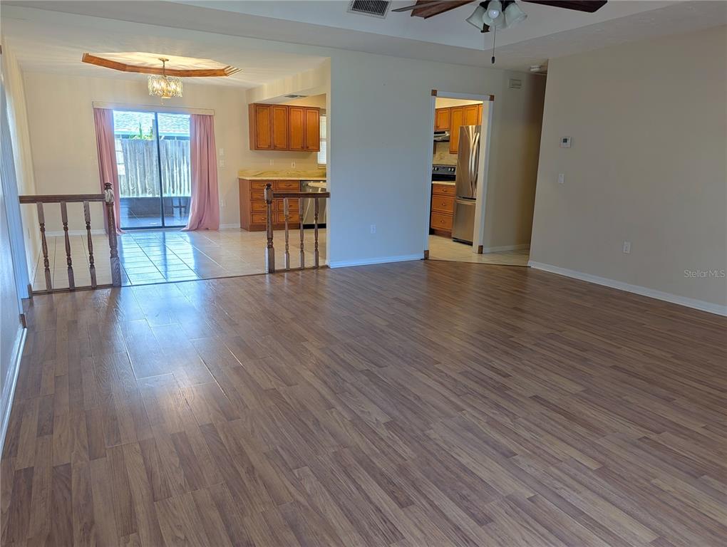 A spacious living area with wood-look flooring leads to a tiled dining space and kitchen — 88 TEMPLE ROAD, VENICE, FL
