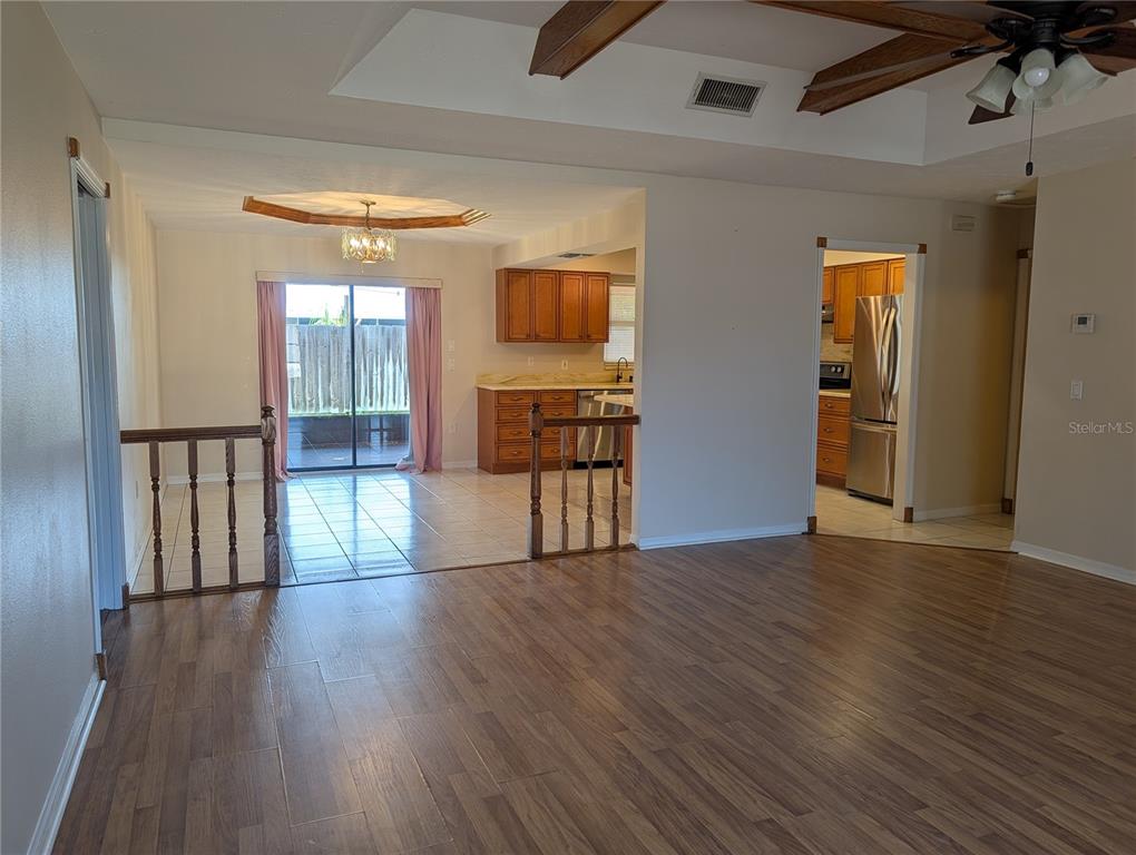 A living area with wood-look flooring leads to a tiled dining space and kitchen — 88 TEMPLE ROAD, VENICE, FL