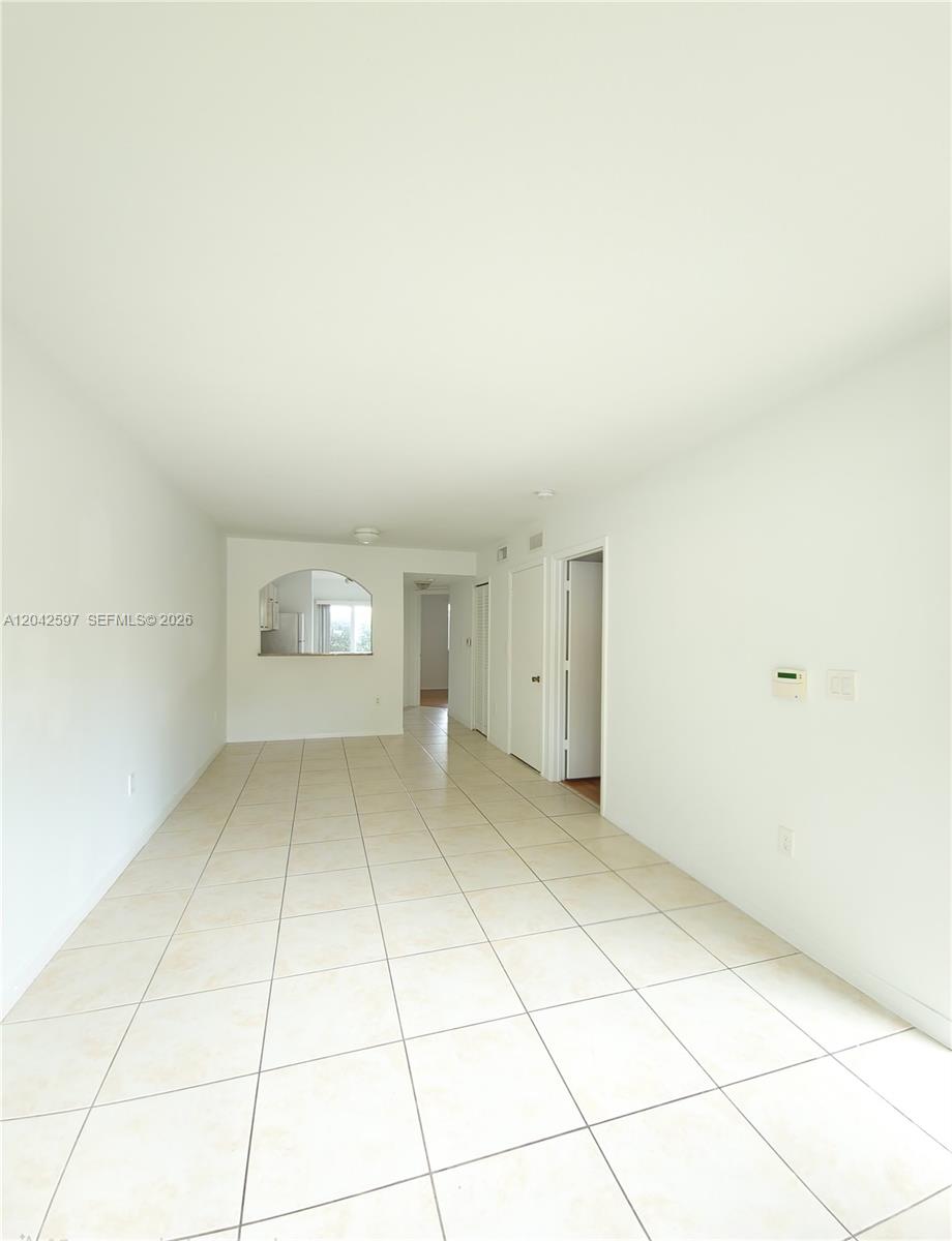 An empty room with white walls and light-colored square floor tiles — 940 NE 33rd Ter # 102, Homestead FL 33033, HOMESTEAD, FL