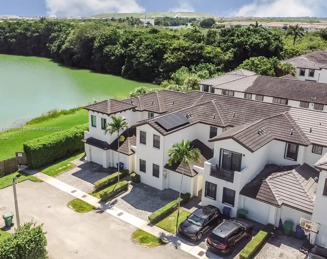 An aerial view shows a multi-story townhouse complex with a lake and green space nearby — 22509 SW 102nd Ave, Miami FL 33190, MIAMI, FL
