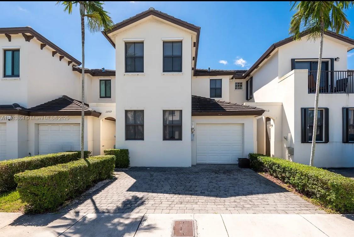 A two-story townhouse exterior features a paved driveway, two garage doors, and manicured hedges — 22509 SW 102nd Ave, Miami FL 33190, MIAMI, FL