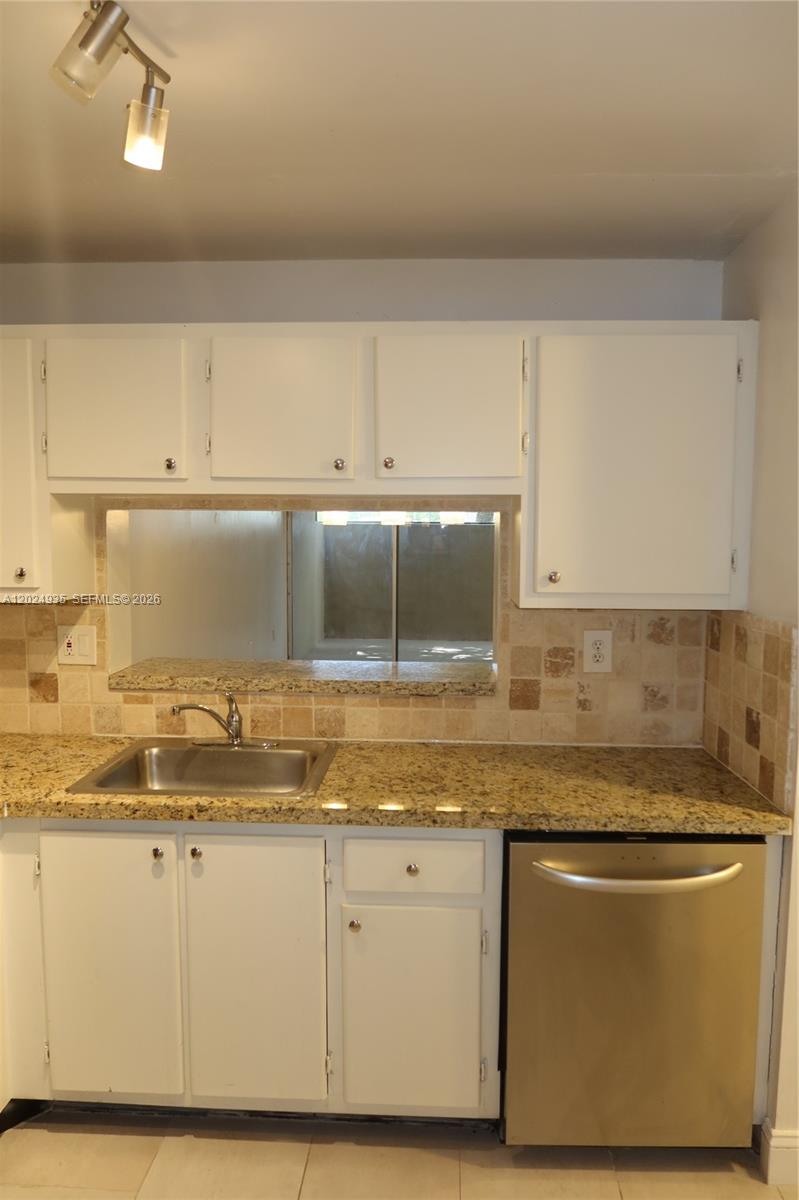 A kitchen features white cabinets, granite countertops, a stainless steel dishwasher, and a tiled backsplash — 10835 SW 112th Ave # 113, Miami FL 33176, MIAMI, FL