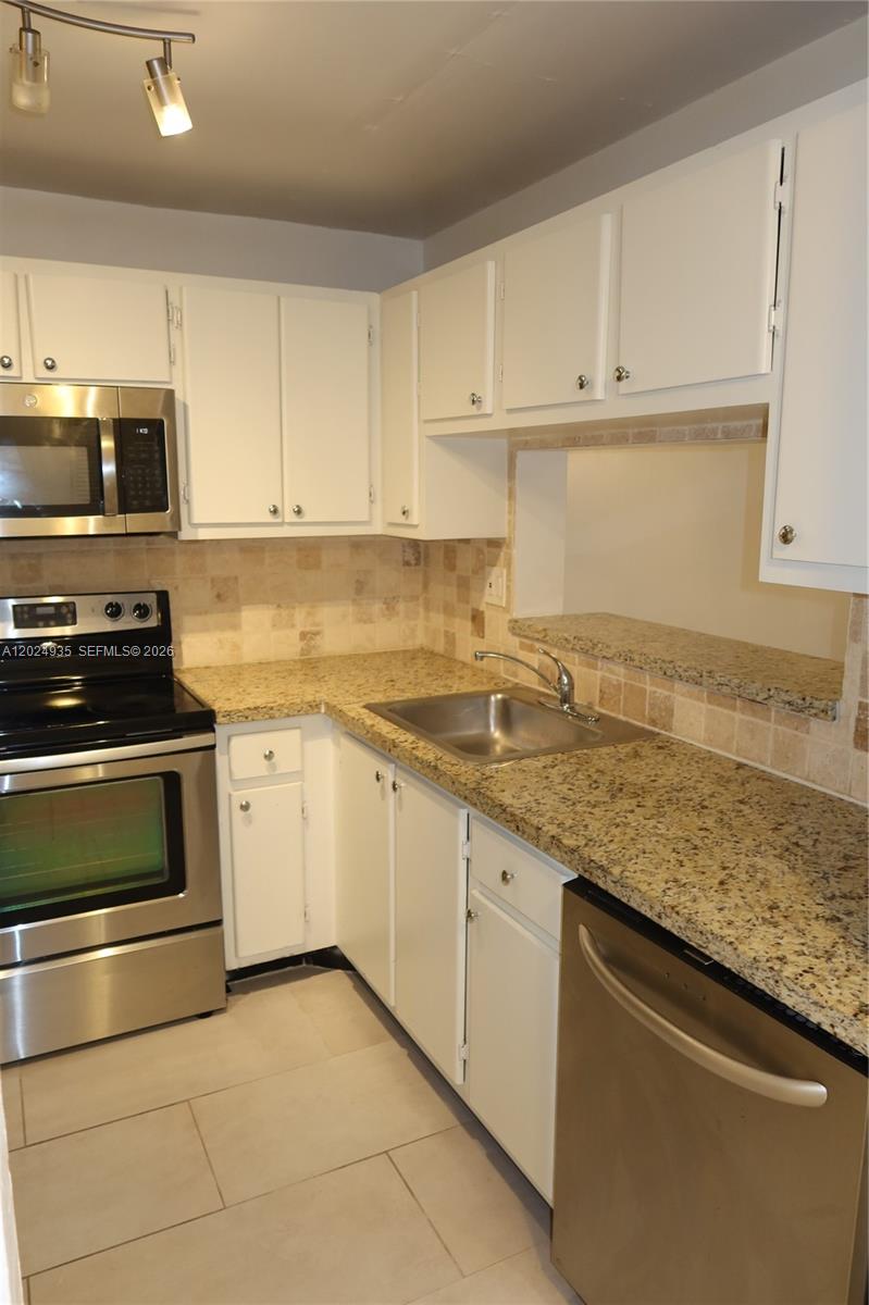 A kitchen features white cabinets, granite countertops, stainless steel appliances, and a tiled backsplash — 10835 SW 112th Ave # 113, Miami FL 33176, MIAMI, FL