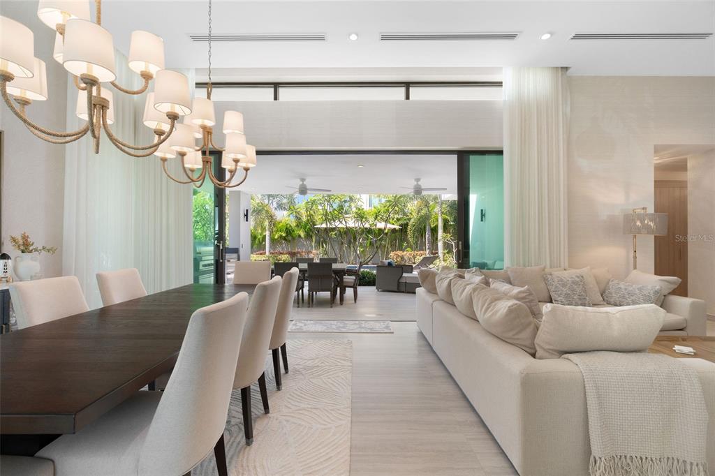 A modern open-concept living and dining area features a large chandelier and sliding glass doors — 32 THE ISLES, DORADO, PR