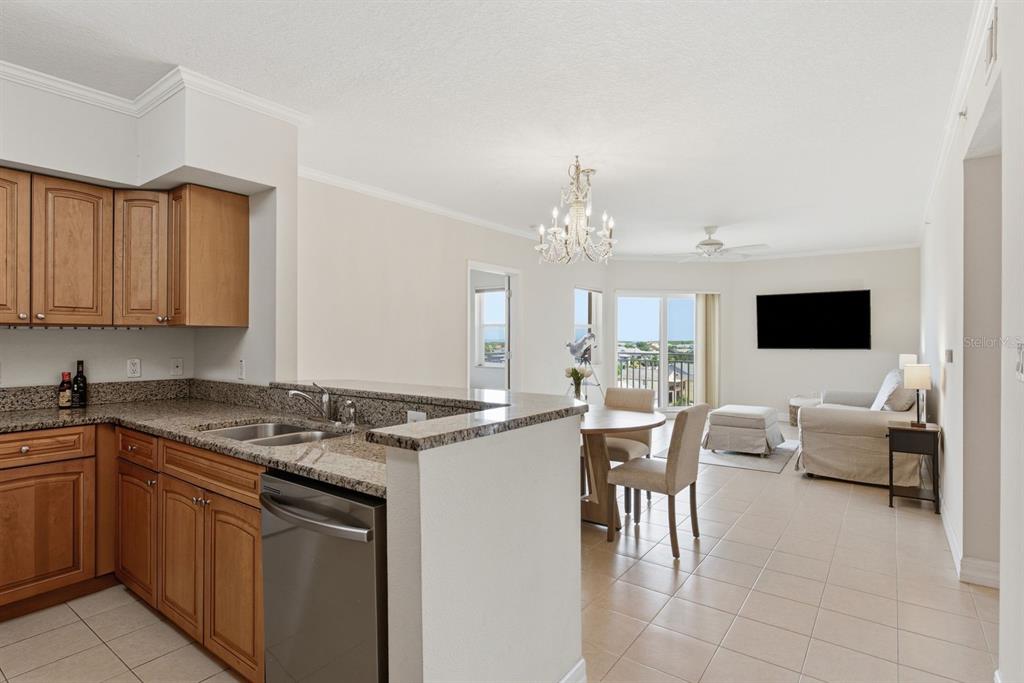 A kitchen with wood cabinets and granite countertops overlooks an open dining and living area — 4516 SEAGULL DRIVE UNIT 701, NEW PORT RICHEY, FL
