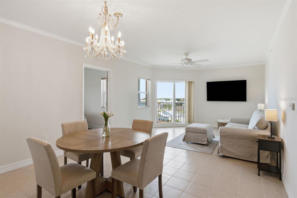A dining area and living room with tile floors, a chandelier, and a balcony view — 4516 SEAGULL DRIVE UNIT 701, NEW PORT RICHEY, FL
