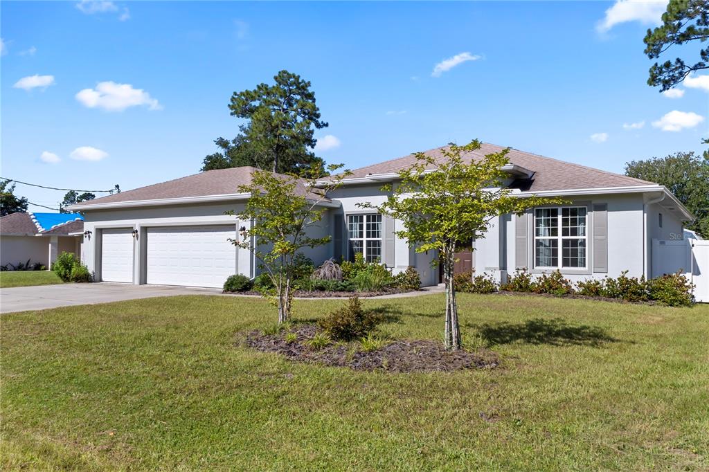 A single-story house with a two-car garage, light-colored stucco exterior, and a front lawn — 39 BOULDER ROCK DRIVE, PALM COAST, FL