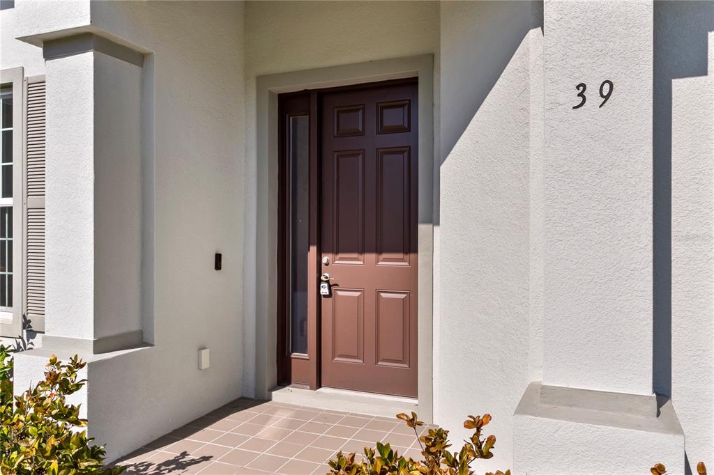 A brown front door with a side window is set into a white stucco entryway — 39 BOULDER ROCK DRIVE, PALM COAST, FL