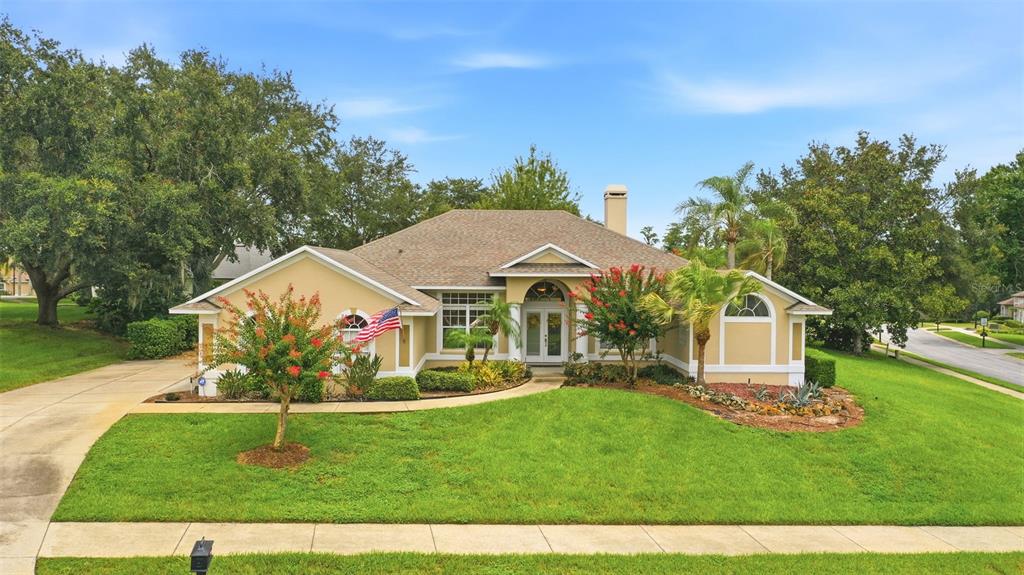 A single-story tan house with a shingled roof, front lawn, and a paved driveway — 11310 SUSANS POINT DRIVE, CLERMONT, FL